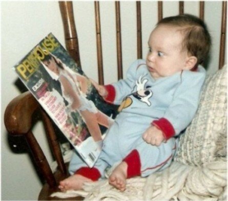 Funny baby looking at magazine